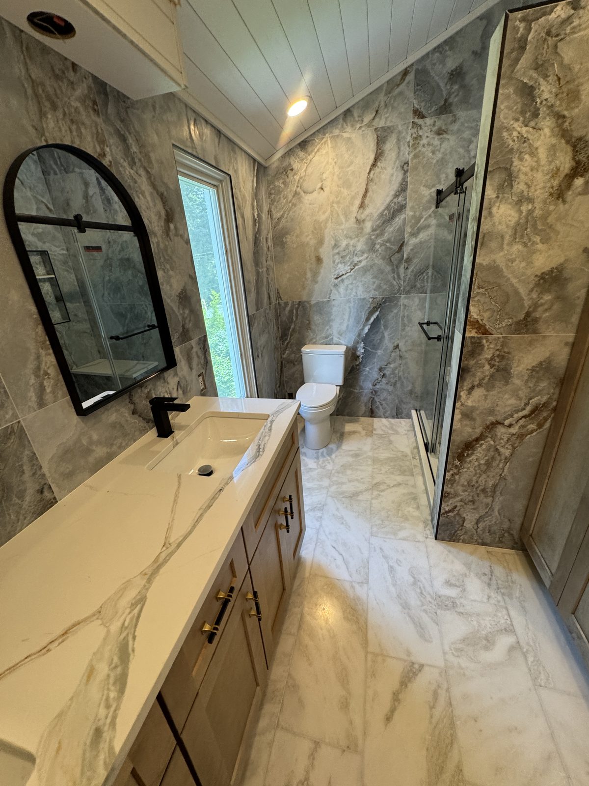 Luxury bathroom remodel by Altieri and Sons with marble tile, glass shower, and brass hardware